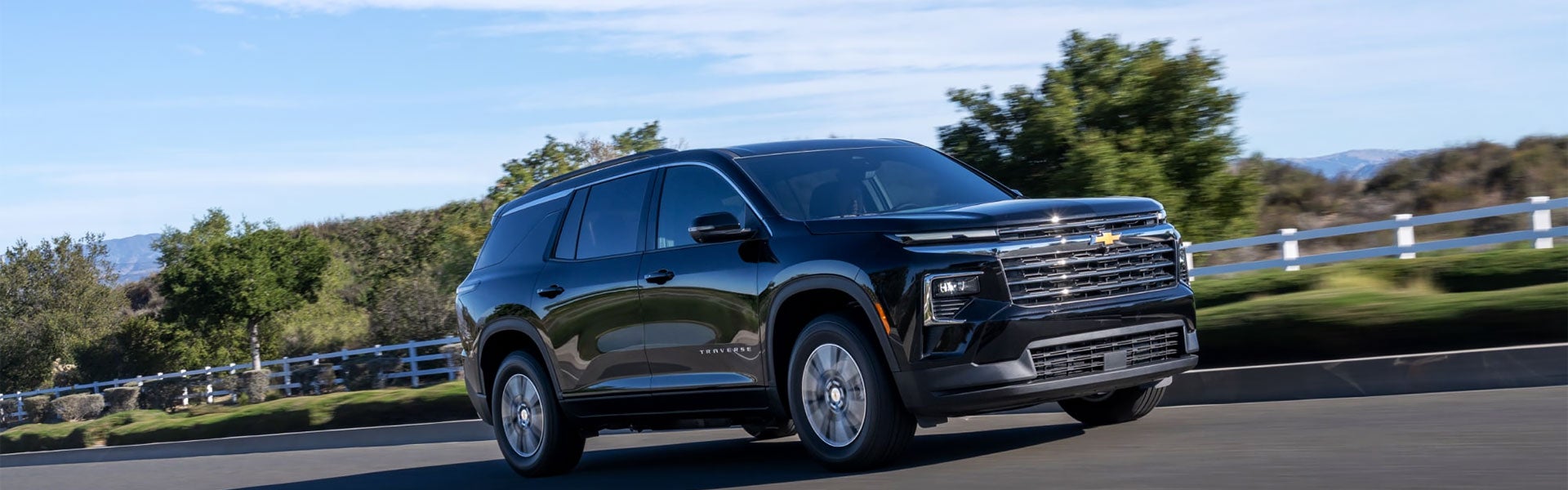 Black Chevrolet Traverse driving along a scenic country road